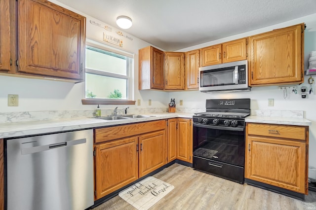 kitchen featuring appliances with stainless steel finishes, sink, and light hardwood / wood-style flooring