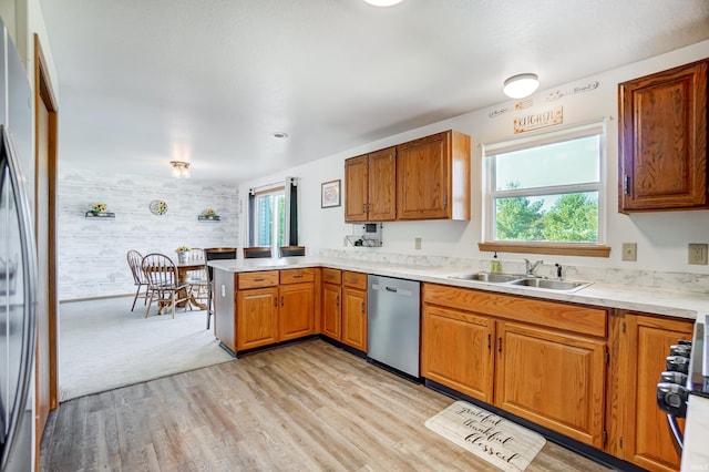 kitchen featuring appliances with stainless steel finishes, sink, light hardwood / wood-style flooring, and kitchen peninsula