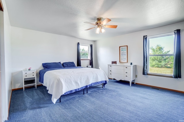 carpeted bedroom with ceiling fan and a textured ceiling