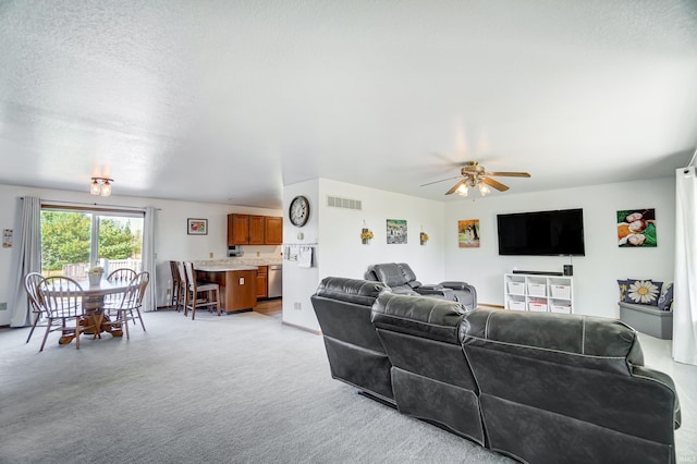 living room featuring light carpet, ceiling fan, and a textured ceiling