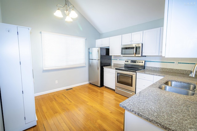 kitchen with vaulted ceiling, appliances with stainless steel finishes, pendant lighting, sink, and white cabinets