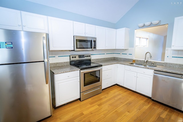 kitchen featuring sink, appliances with stainless steel finishes, light hardwood / wood-style floors, white cabinets, and vaulted ceiling