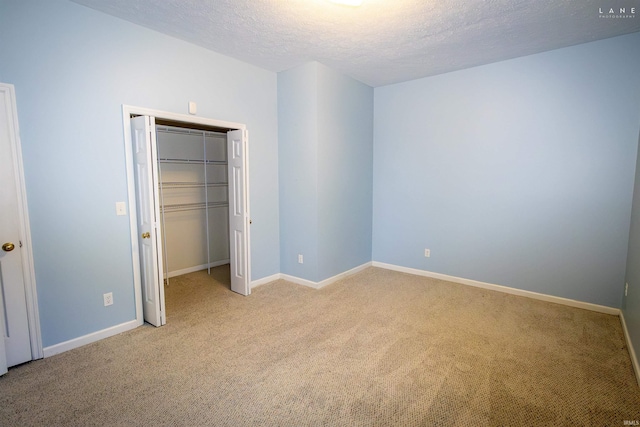 unfurnished bedroom featuring light carpet, a textured ceiling, and a closet