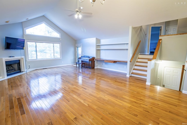 unfurnished living room with ceiling fan, high vaulted ceiling, light wood-type flooring, and built in shelves