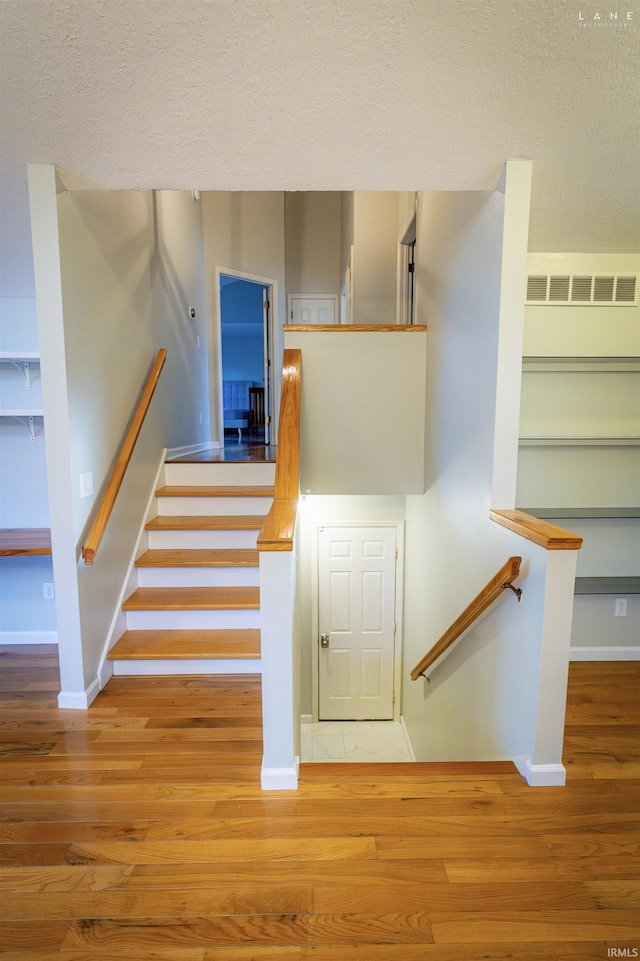 staircase with hardwood / wood-style flooring and a textured ceiling