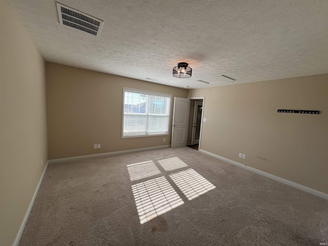 spare room featuring light carpet and a textured ceiling