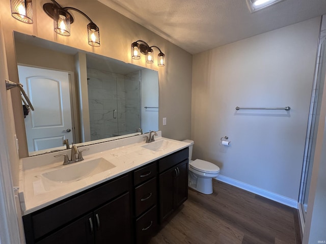 bathroom with wood-type flooring, vanity, an enclosed shower, toilet, and a textured ceiling