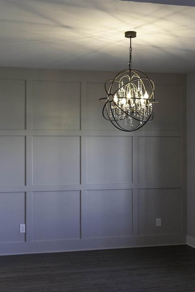 unfurnished dining area with dark wood-type flooring and an inviting chandelier