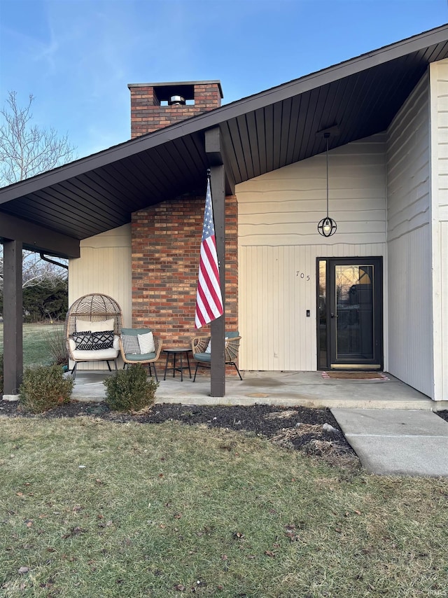 property entrance featuring a patio and a lawn