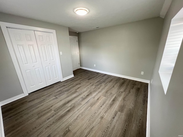 unfurnished bedroom featuring dark wood-type flooring and a closet