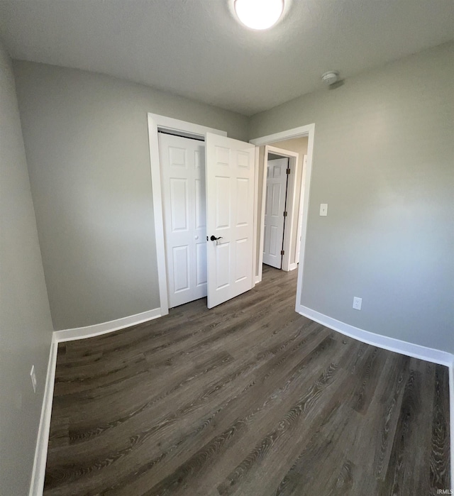 unfurnished bedroom with dark hardwood / wood-style flooring and a closet