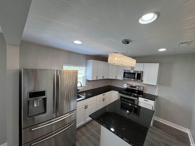 kitchen with appliances with stainless steel finishes, sink, white cabinets, decorative backsplash, and hanging light fixtures