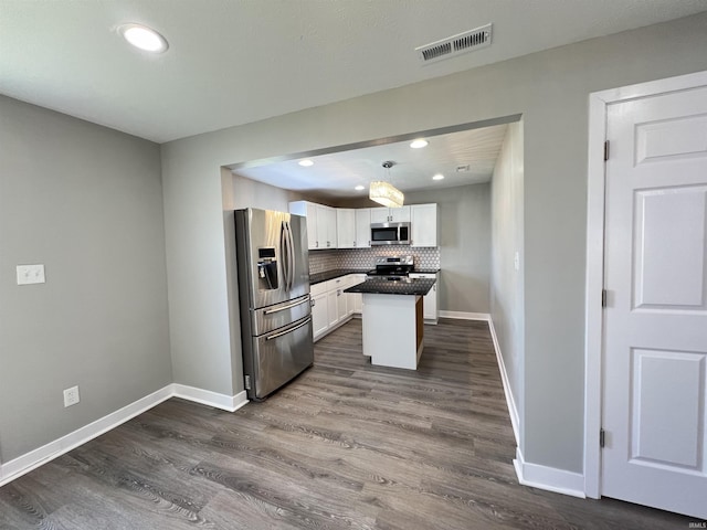 kitchen with dark wood-type flooring, appliances with stainless steel finishes, a center island, tasteful backsplash, and white cabinets