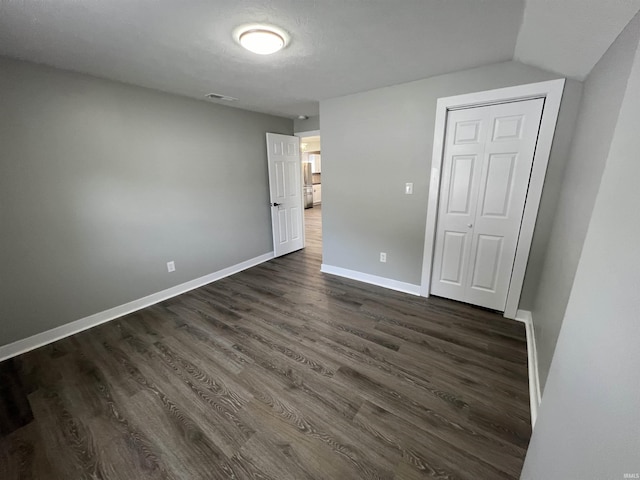 unfurnished bedroom featuring a closet and dark hardwood / wood-style floors