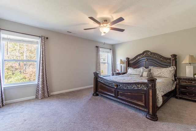 carpeted bedroom with ceiling fan and a textured ceiling