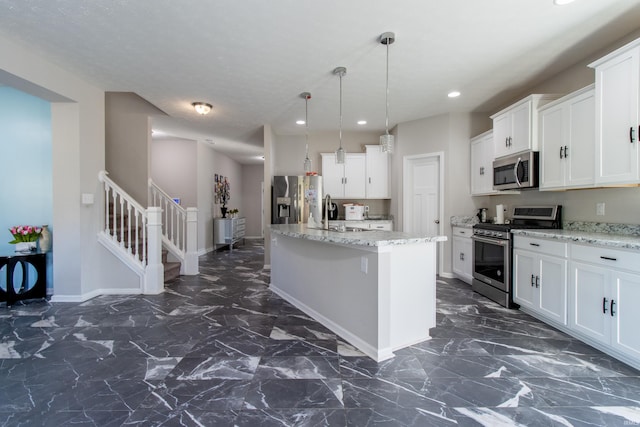 kitchen with light stone countertops, stainless steel appliances, a center island, and white cabinets