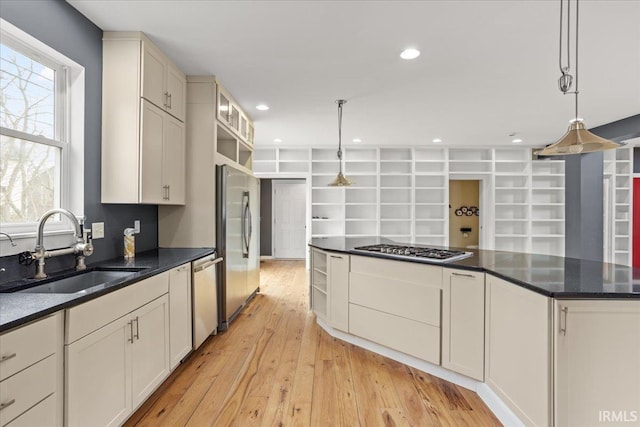 kitchen with appliances with stainless steel finishes, sink, pendant lighting, and light hardwood / wood-style floors