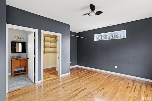 unfurnished bedroom with sink, a spacious closet, and light hardwood / wood-style floors