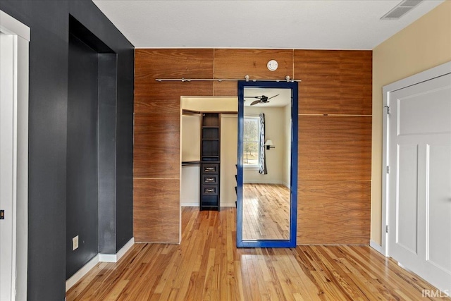 hallway featuring wooden walls and light wood-type flooring