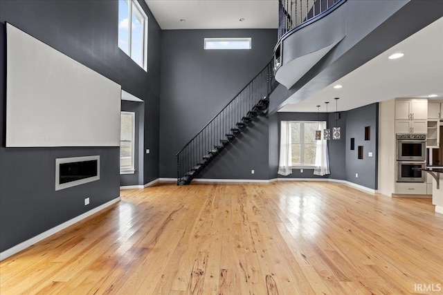 unfurnished living room featuring a high ceiling, a chandelier, and light wood-type flooring