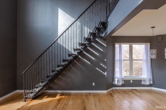 stairs with hardwood / wood-style flooring and a high ceiling