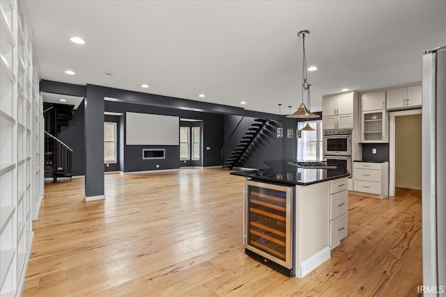 kitchen with wine cooler, white cabinets, a kitchen island, and pendant lighting