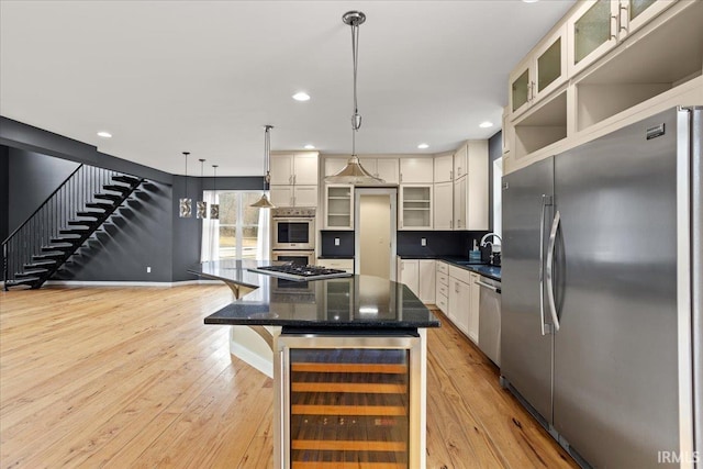 kitchen with pendant lighting, appliances with stainless steel finishes, white cabinetry, wine cooler, and a kitchen island