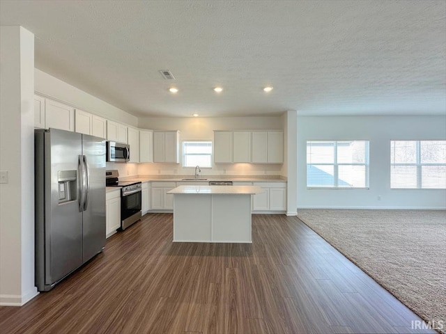 kitchen with sink, white cabinetry, a center island, a textured ceiling, and stainless steel appliances