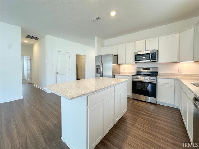 kitchen with a kitchen island, appliances with stainless steel finishes, dark hardwood / wood-style floors, and white cabinets