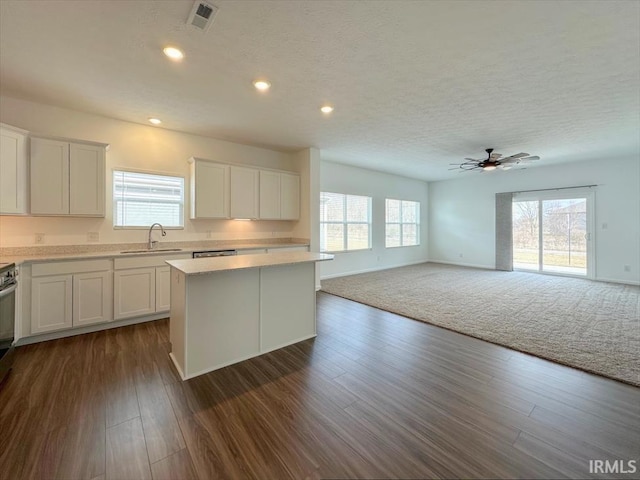 kitchen featuring sink, dark hardwood / wood-style floors, a center island, and white cabinets