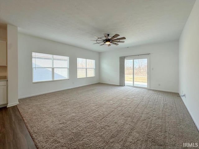 spare room with ceiling fan, dark carpet, and a textured ceiling