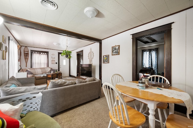 interior space featuring light carpet, beamed ceiling, and ornamental molding