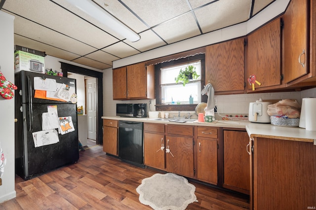 kitchen with dark hardwood / wood-style flooring, a drop ceiling, sink, and black appliances