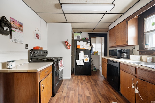 kitchen featuring sink, a drop ceiling, black appliances, and wood-type flooring