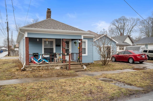 bungalow featuring covered porch and a front lawn