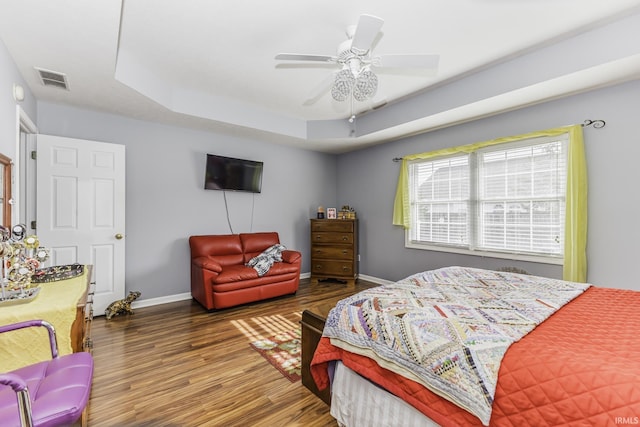 bedroom featuring a raised ceiling, hardwood / wood-style flooring, and ceiling fan