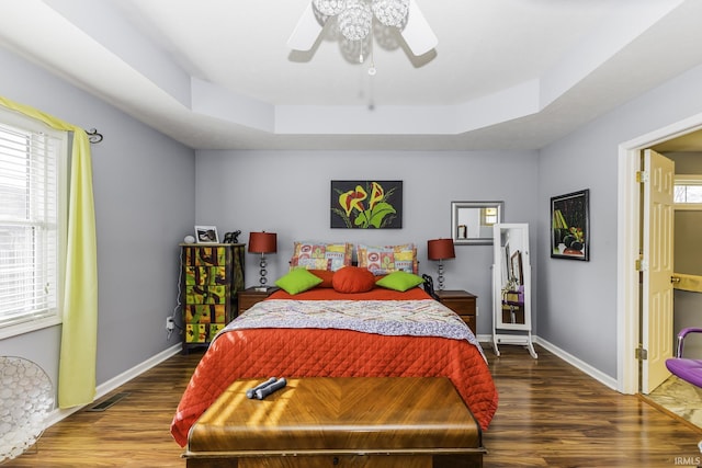 bedroom with a raised ceiling, hardwood / wood-style floors, and ceiling fan