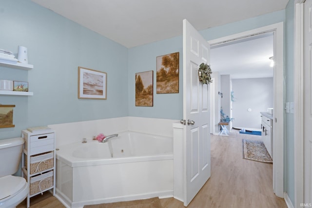 bathroom with hardwood / wood-style flooring, vanity, a bath, and toilet