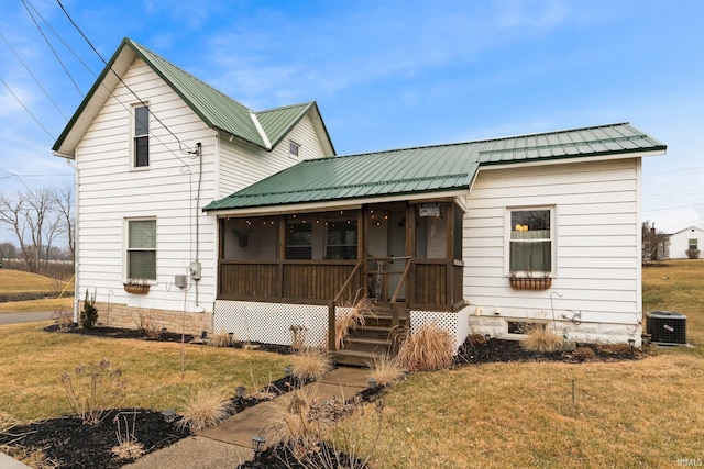 view of front of home with cooling unit, a sunroom, and a front yard