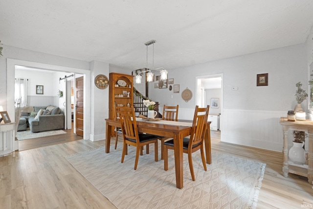 dining space with light hardwood / wood-style floors and a notable chandelier