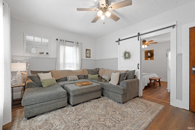 living room featuring a barn door, dark hardwood / wood-style floors, and ceiling fan