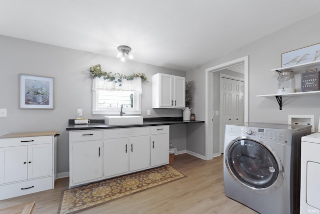 washroom with cabinets, light hardwood / wood-style floors, sink, and washing machine and dryer