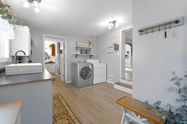 washroom featuring sink, washer and dryer, and light wood-type flooring