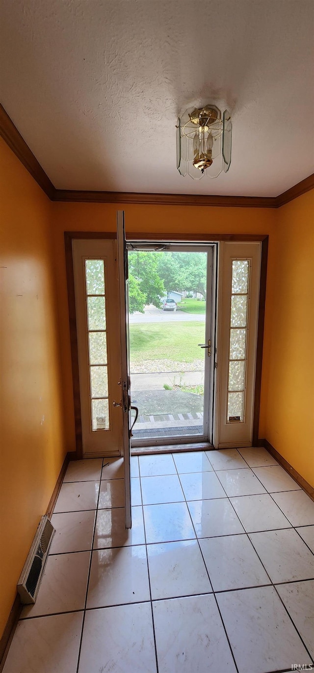 doorway featuring crown molding, a textured ceiling, and light tile patterned floors