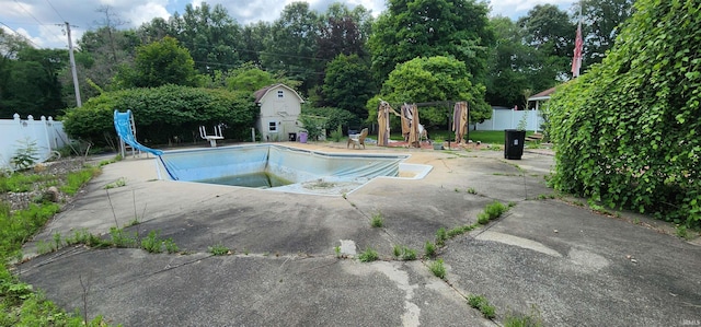 view of swimming pool with a water slide and a patio