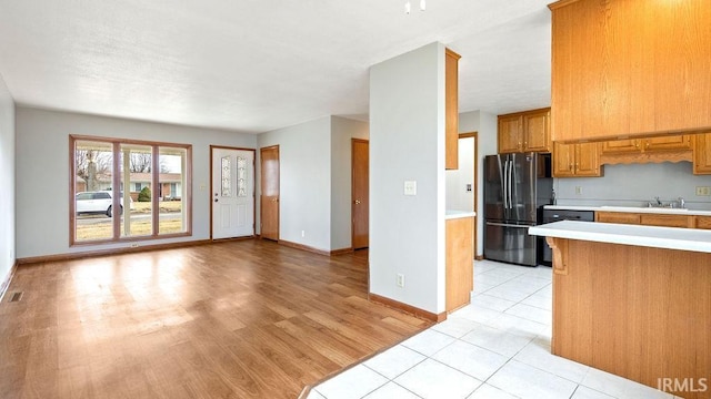 kitchen with light hardwood / wood-style floors, dishwasher, and black fridge