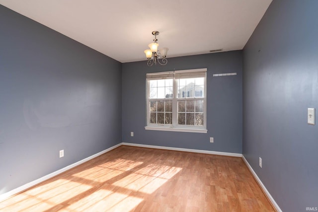 spare room featuring a notable chandelier and wood-type flooring