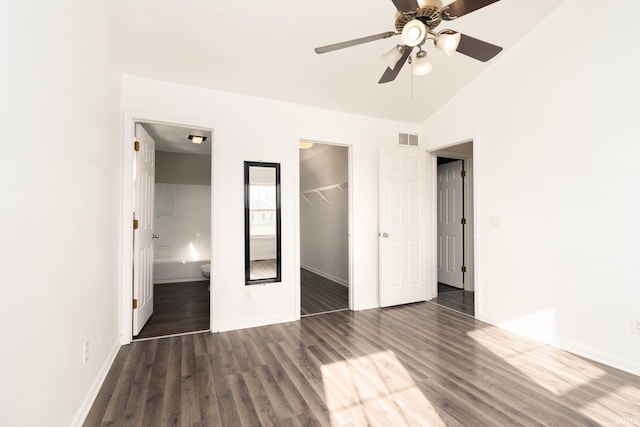 unfurnished bedroom featuring dark wood-type flooring, ensuite bath, a spacious closet, a closet, and ceiling fan