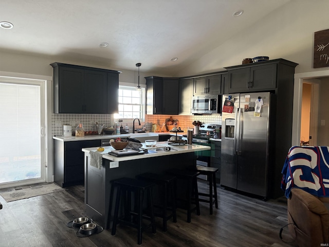 kitchen featuring a center island, vaulted ceiling, hanging light fixtures, dark hardwood / wood-style flooring, and stainless steel appliances