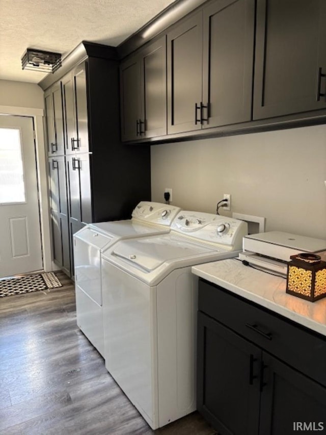 laundry room featuring cabinets, dark hardwood / wood-style flooring, washer and dryer, and a textured ceiling